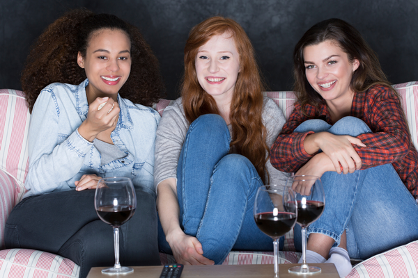 Three woman sat on the couch and watching a movie together